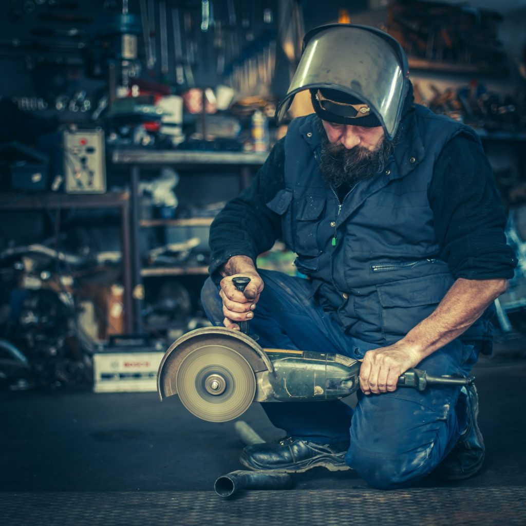 Metal grinding on steel spare part in workshop